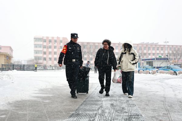 铁路民警在进站口帮助携带行李较多的旅客提拎行李、顺利乘车。——摄影袁磊.JPG