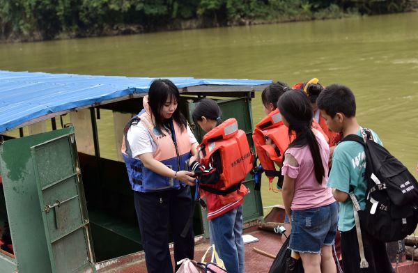 图为：县交通运输综合行政执法大队工作员在指导学生穿救生衣。（龙梦前 摄）2.JPG
