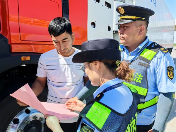 05221747915460323851.jpg 图2:执法人员向货运司机发放超限运输法律法规宣传资料.jpg