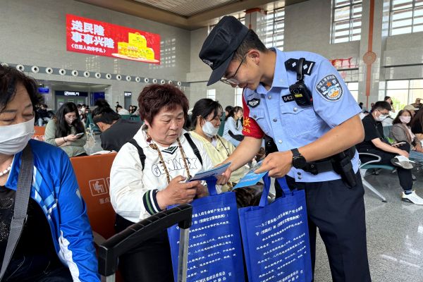 临河站派出所执勤民警在站内发放宣传资料，讲解安全知识。——摄影张璐.jpg