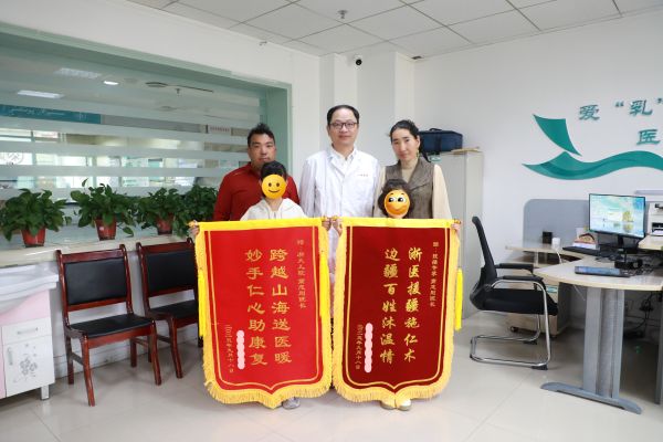两个小患儿赠送高志刚（中）感谢锦旗。胡珺 摄.jpg