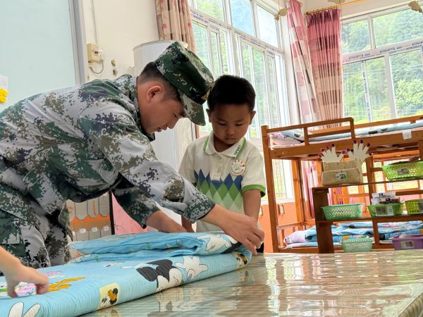 图为 退役军人志愿者指导“豆腐块”被子的叠放现场（许青青 摄）.jpg