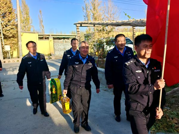 沙雅县公安局交通管理大队党员干部志愿服务队手持党旗、携带慰问物资，走进托依堡勒迪镇铁热克村，准备前往孤寡老人阿依谢姆·米依普家中开展走访慰问.jpg